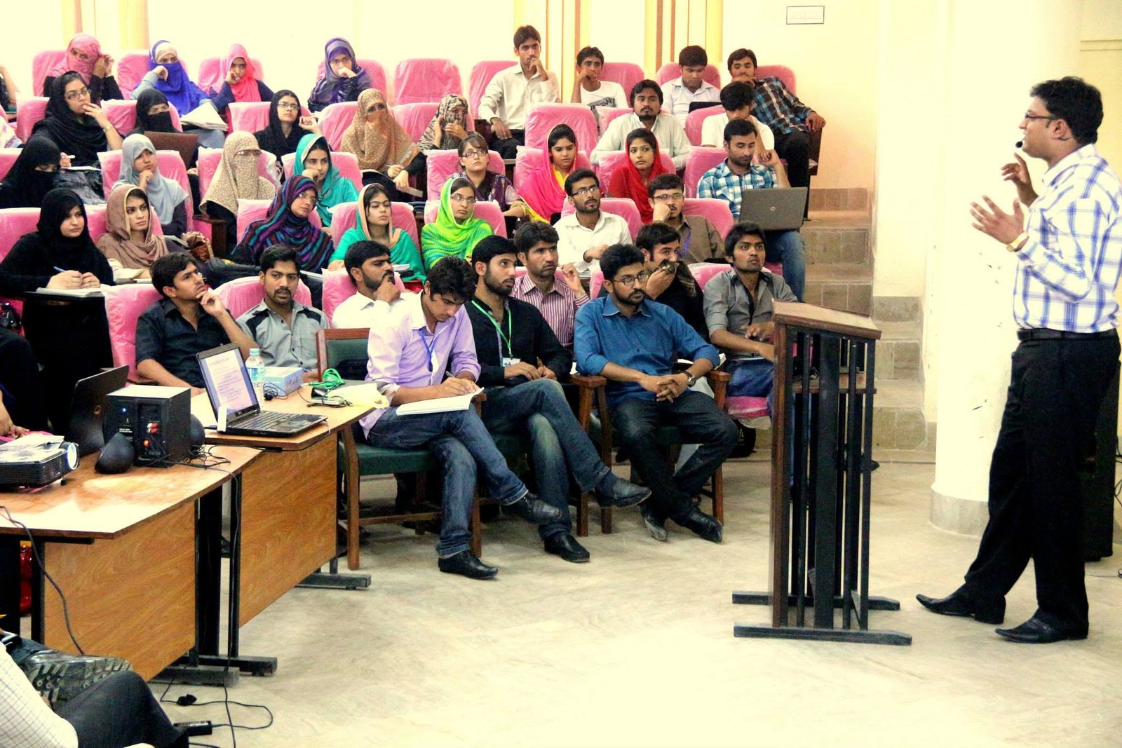 Ghulam Sarwar presenting to students in a large auditorium